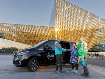 Guide greeting travelers outside Harpa concert hall for the private 3 hour Reykjavik Driving Tour