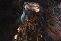 Visitors walking through a lava cave with dramatic volcanic rock formations