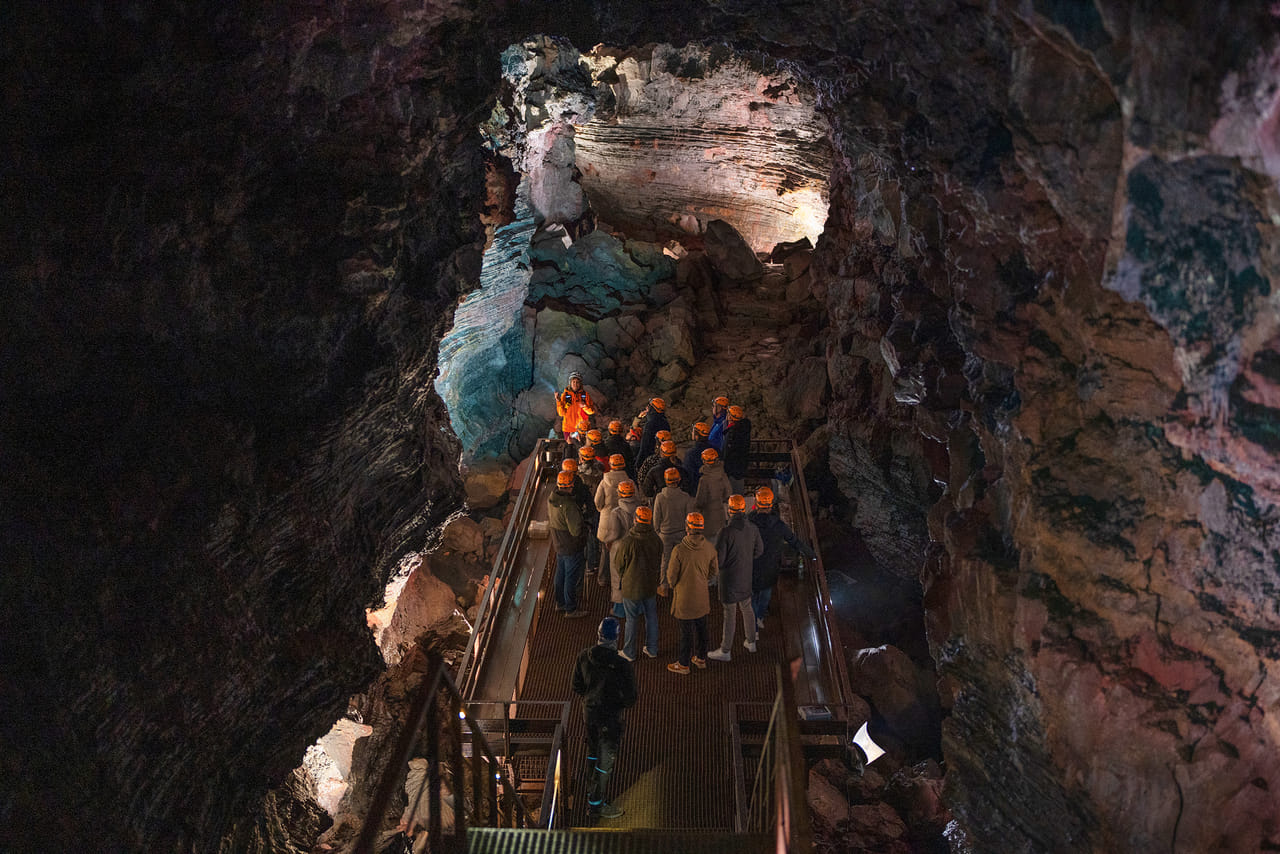 Visitors walking through a lava cave with dramatic volcanic rock formations