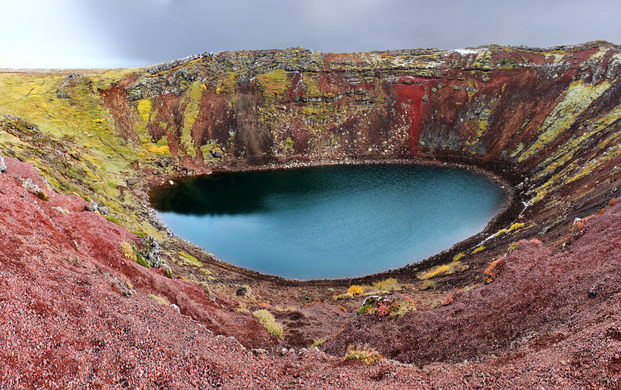 Red lava rock and green moss decorating the rim of Kerid volcanic crater