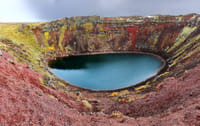 Red lava rock and green moss decorating the rim of Kerid volcanic crater