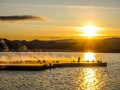 People enjoying the warm waters in the floating geothermal pools at Vök baths during sunset