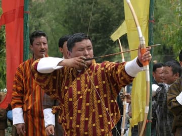 An archer is traditional dress taking aim