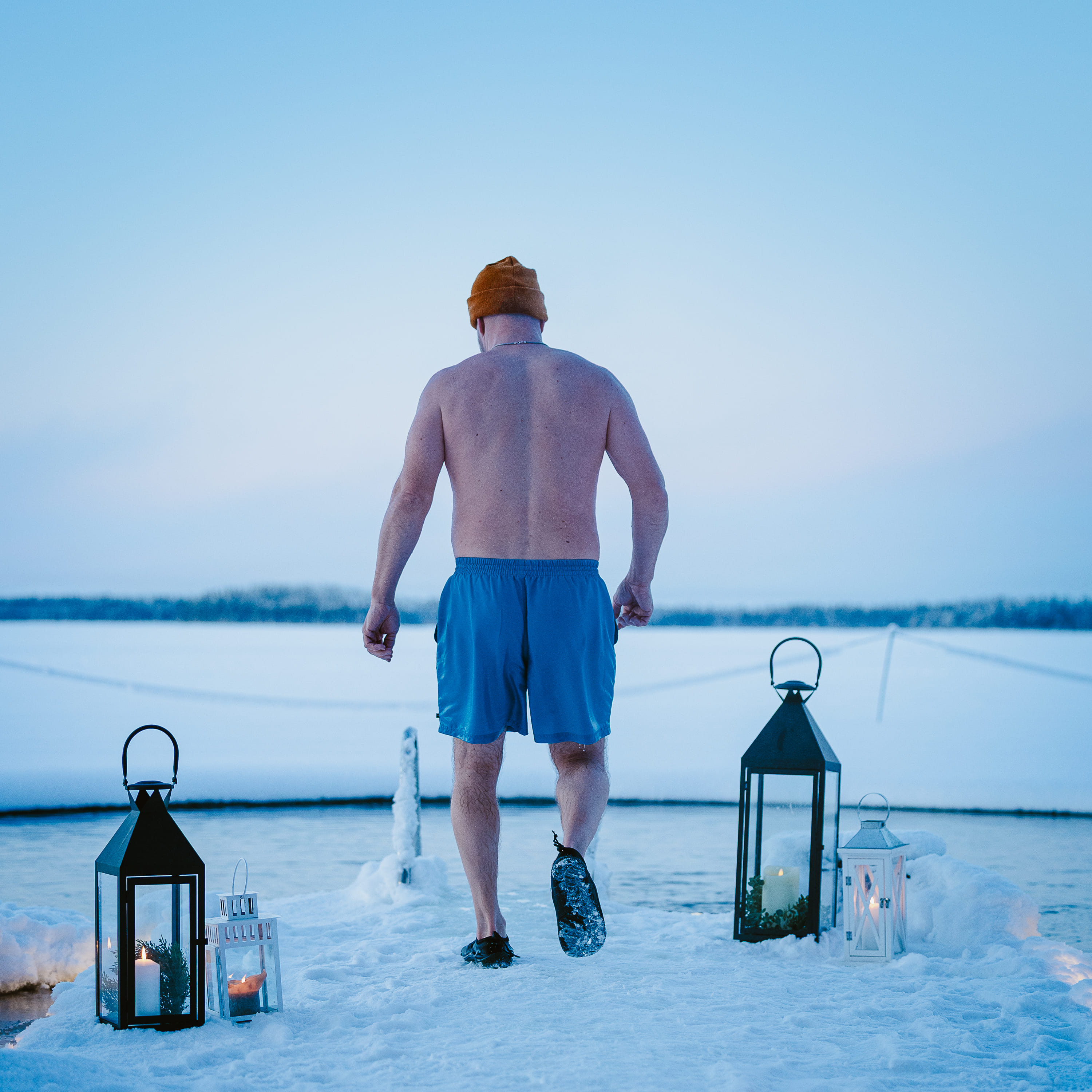 A man walking to frozen ice with an ice swimming spot.