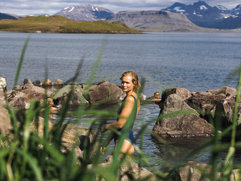 A guest taking a bath in the hot springs in Hvammsvik