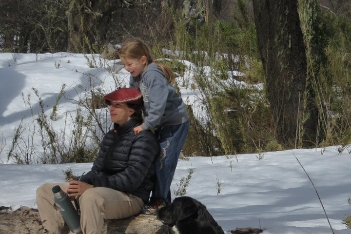 Travelers and the tour dog enjoying a moment together in the snowy forest during the San Martín de los Andes private 4x4 tour