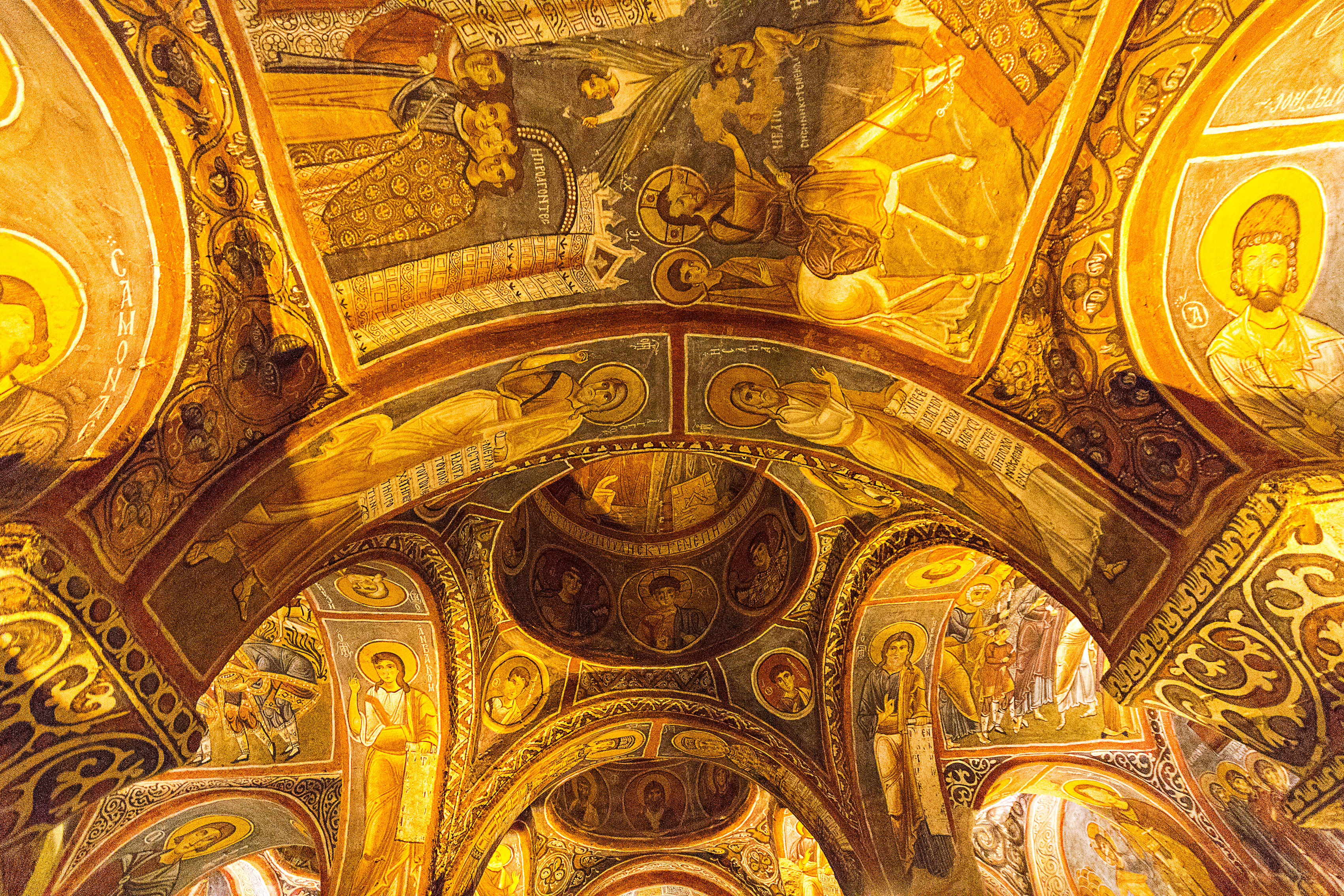“Interior of the Dark Church in Cappadocia, showing vibrant Byzantine frescoes on cave walls illuminated by soft light.”
