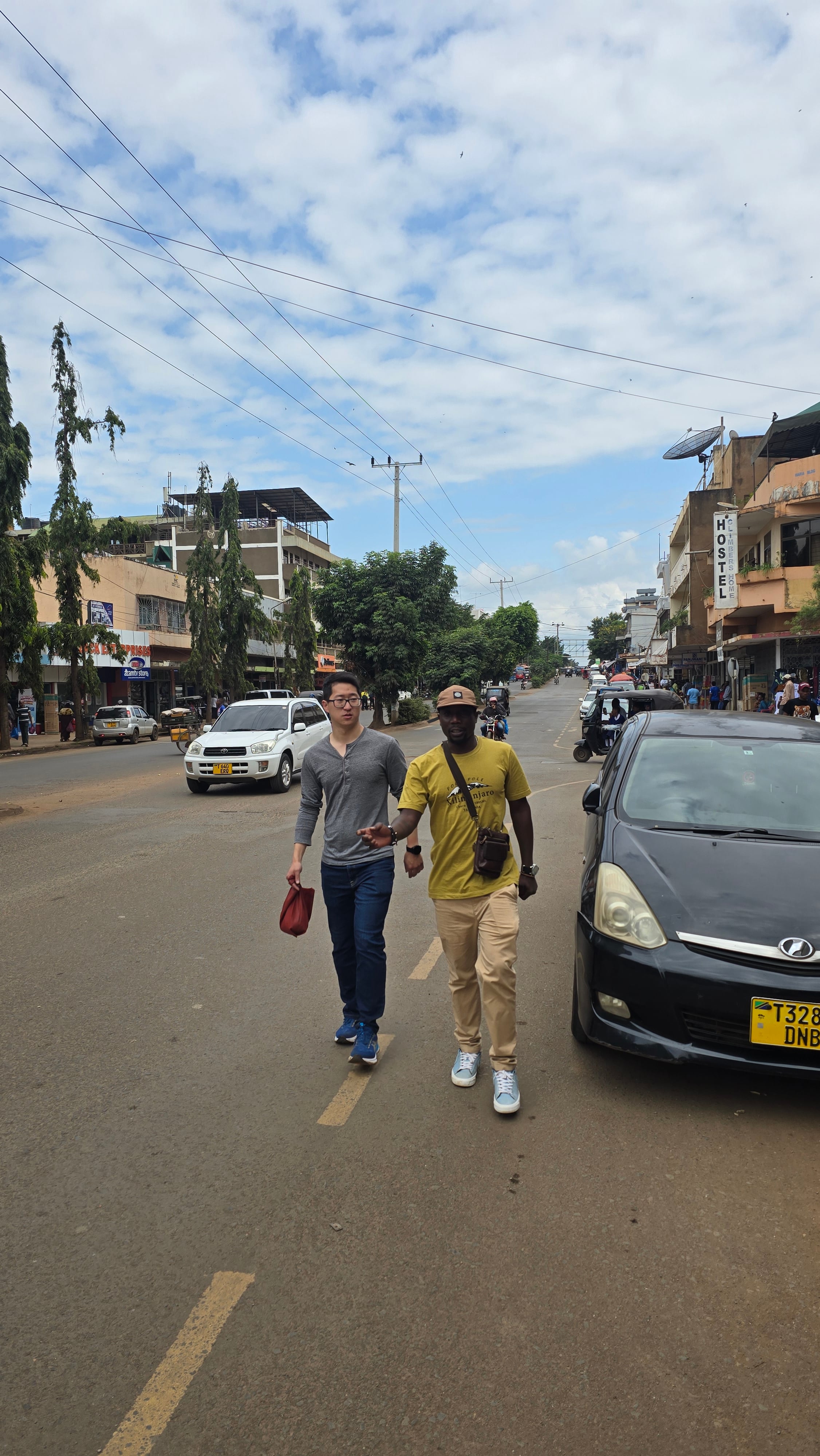 A local guide walking with a traveler down a street in Moshi town.