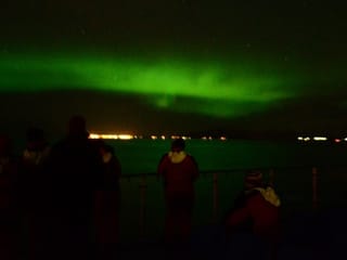 Aurora Borealis glowing above a boat near Reykjavík at night