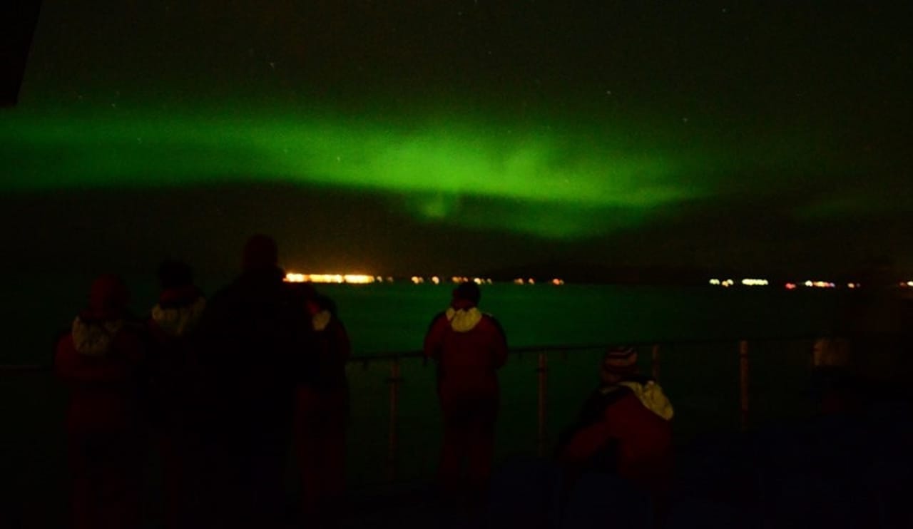 Aurora Borealis glowing above a boat near Reykjavík at night