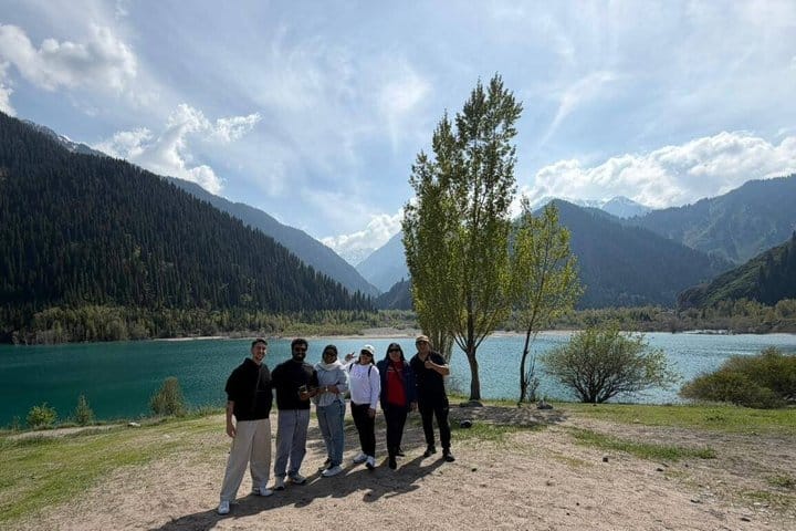 Tourists standing near Issyk Lake with mountain scenery in the background during a guided tour.