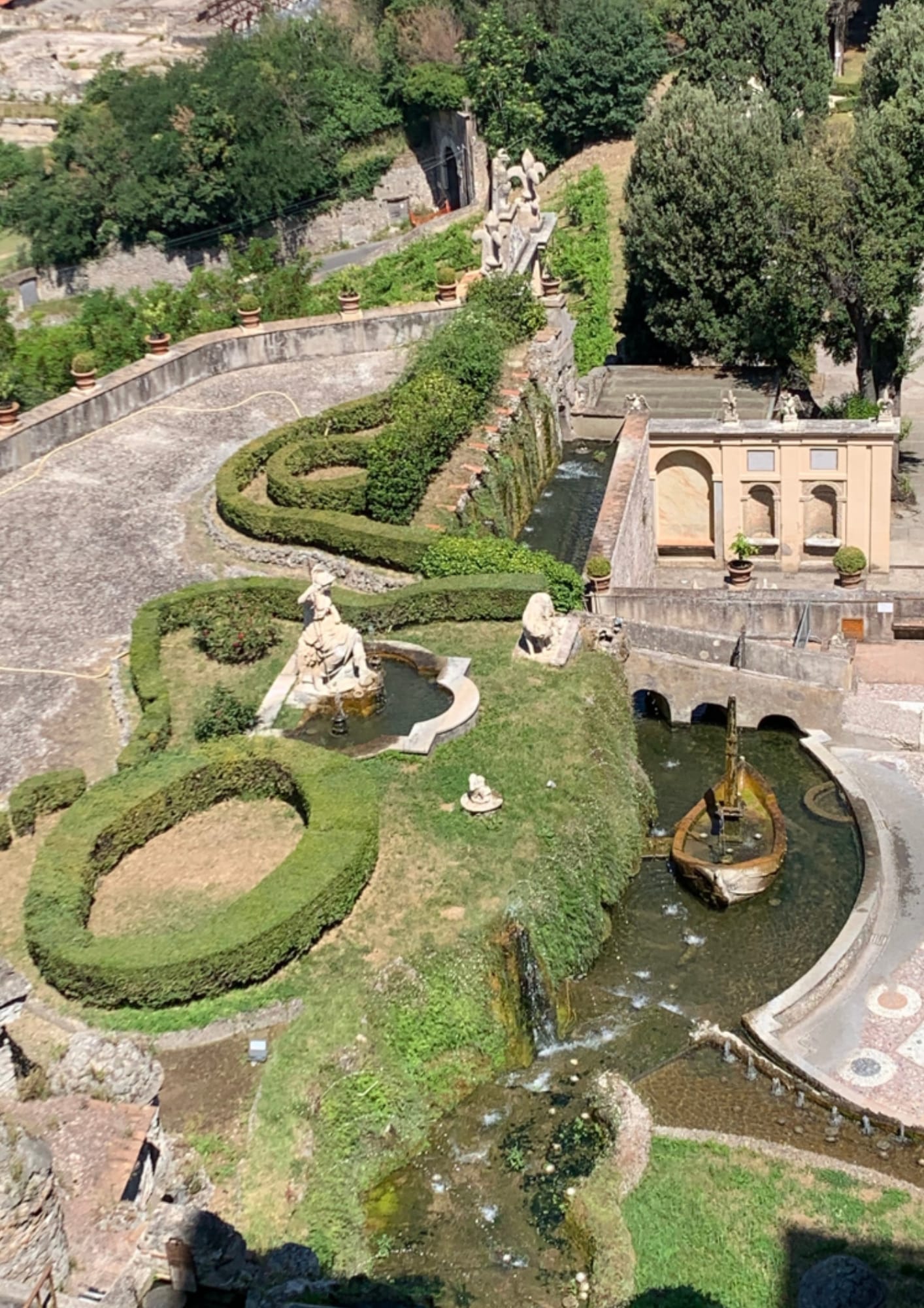 Aerial view of Villa d’Este gardens in Tivoli, with clipped hedges, statues, terraces, and fountains.