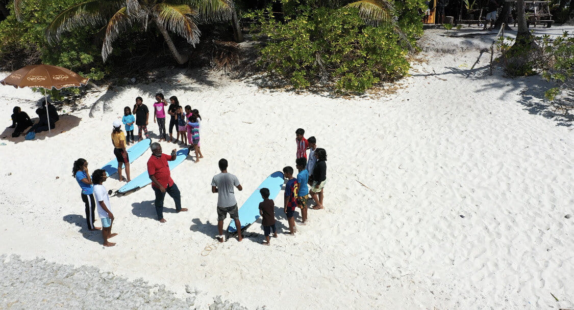 A group of students attending a surf theory class on the beach with Arifiyaalho Surf School in Fuvahmulah.