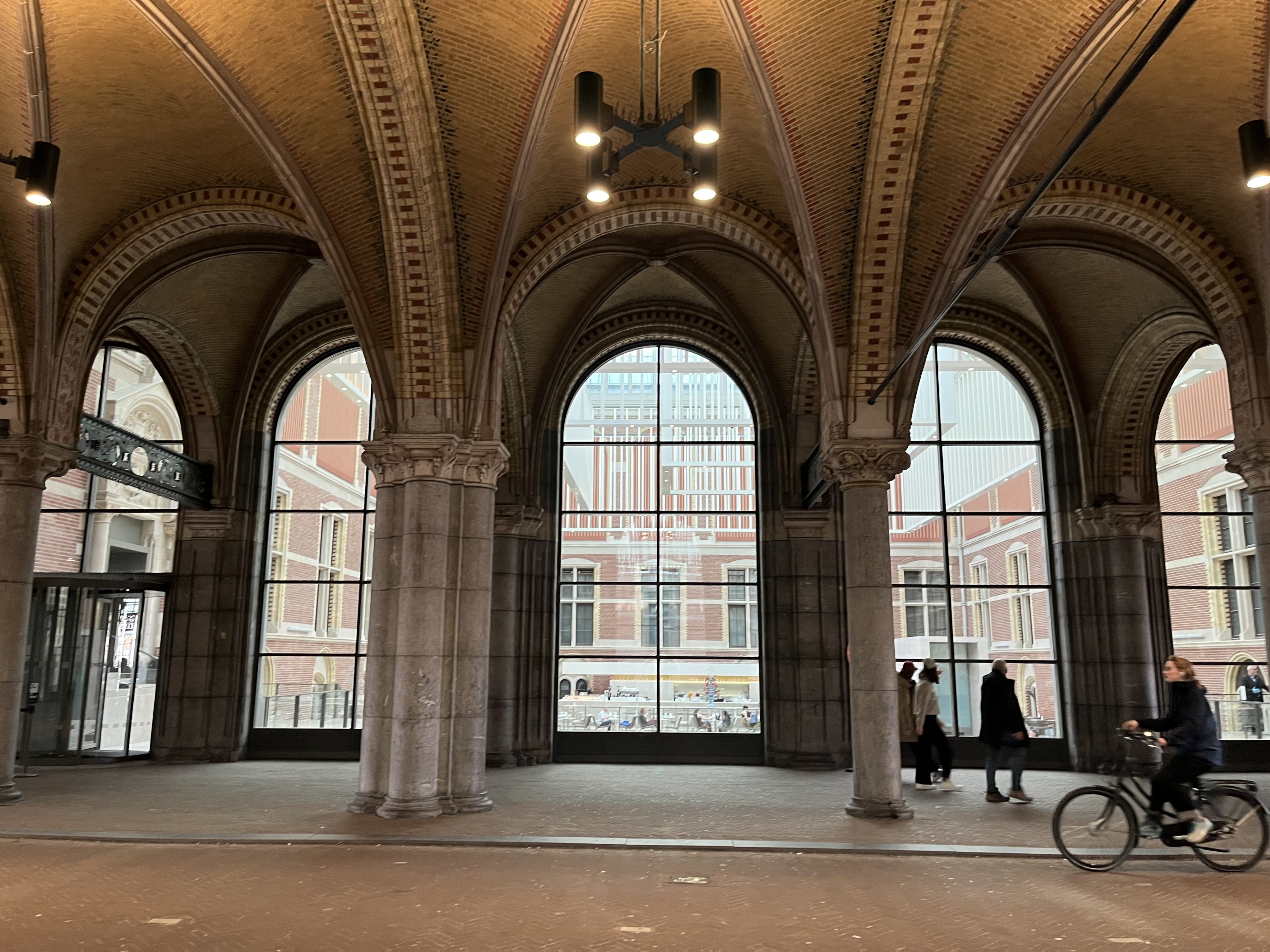 Rijksmuseum passage in Amsterdam with cyclists during private hop-on hop-off sightseeing tour