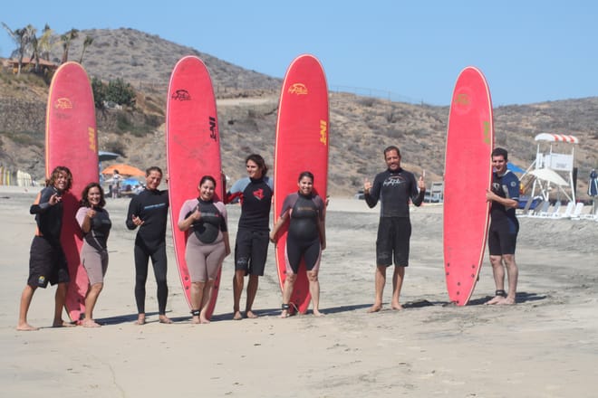 Group of beginner surfers holding surfboards on Cerritos Beach near Los Cabos