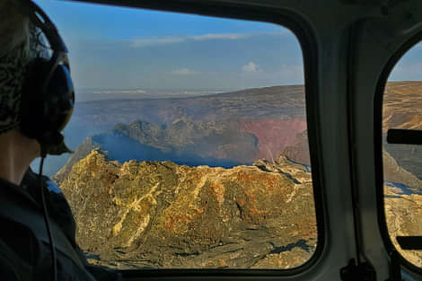 Passenger looking out the window at a large crater