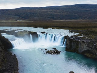 Large waterfall flowing into a serene pool