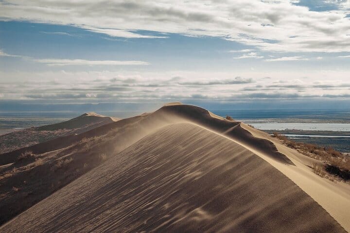 Large sand dune in Altyn-Emel National Park surrounded by desert mountains.