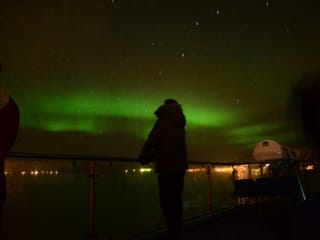 Green Northern Lights reflecting over the ocean during a night cruise