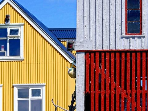Detail of a yellow corrugated iron building next to an older grey and red wooden building