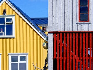 Detail of a yellow corrugated iron building next to an older grey and red wooden building