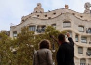 The tour guide explains the façade of Casa Milà to a guest