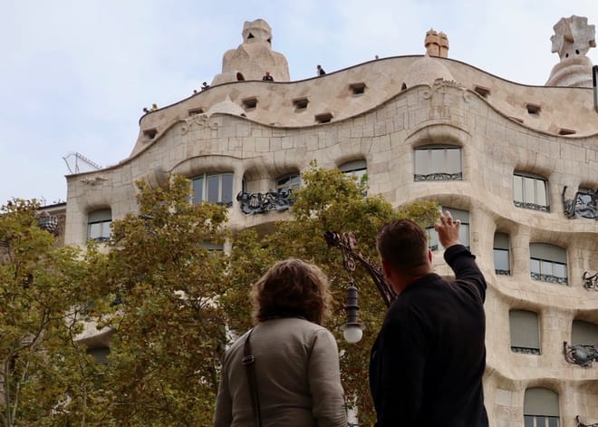 The tour guide explains the façade of Casa Milà to a guest