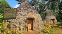 ​A traditional grass-thatched Chagga house surrounded by green foliage on a cultural tour in Marangu, Kilimanjaro.
