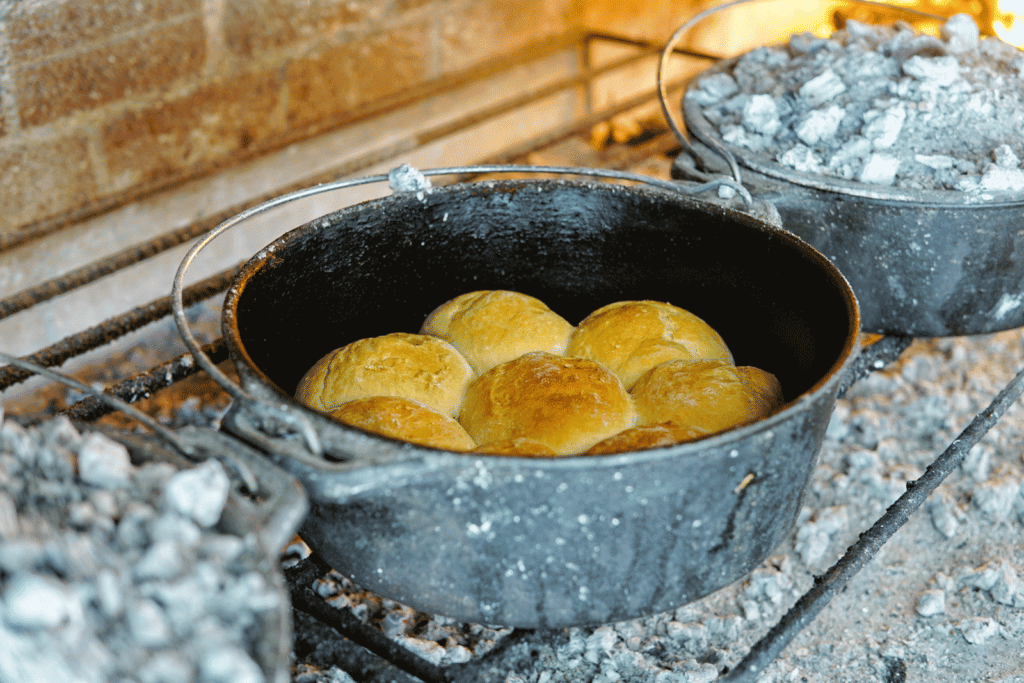 Golden potbrood bread baking in a cast-iron pot over hot coals during the Middelvlei Wine Blending Experience in Stellenbosch.