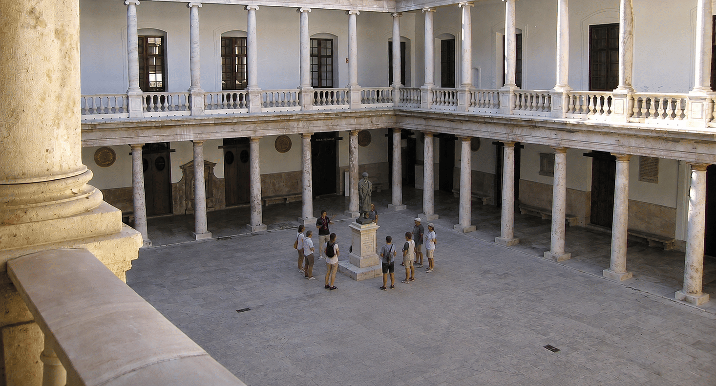 Small group gathered around a guide in the historic cloister courtyard of La Nau University in Valencia