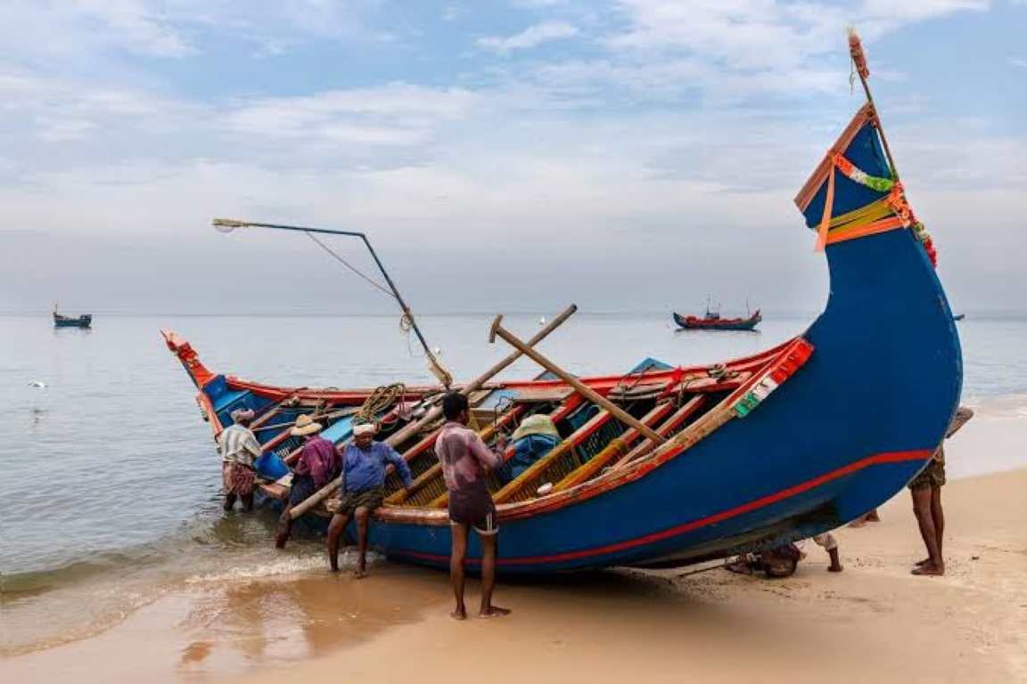 Fishermen beside a colourful fishing boat on the Kerala coast