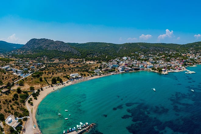 Aerial view of the curved beach and blue water at Agia Marina