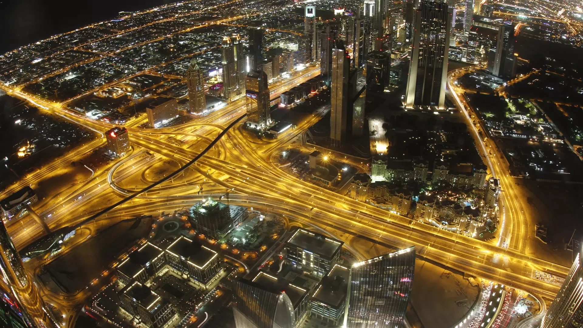 Night view of the Sheikh Zayed Road interchange, its sweeping ribbons of traffic light threading between skyscrapers, seen from Burj Khalifa