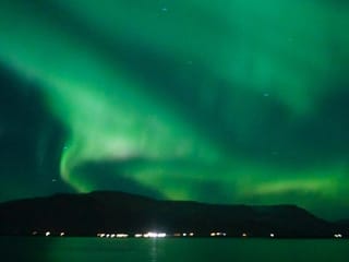 Tour passengers photographing the Northern Lights from a boat deck