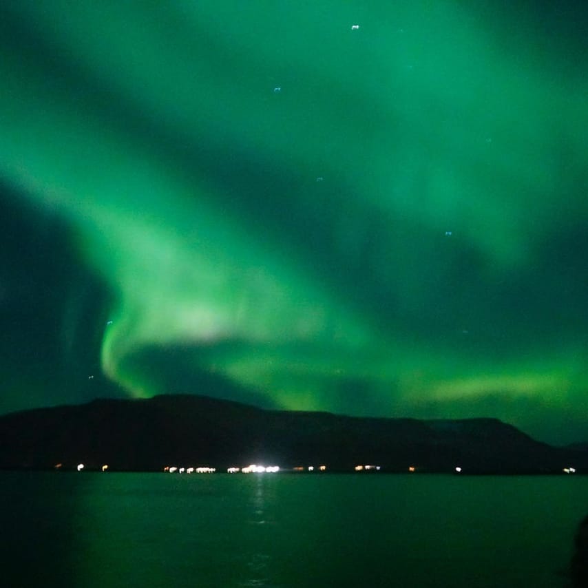Tour passengers photographing the Northern Lights from a boat deck