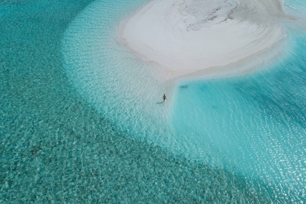 An aerial drone photo of a woman walking on a sandbank