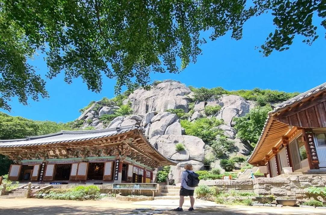 Traditional Beomeosa temple buildings set against rocky mountain scenery.