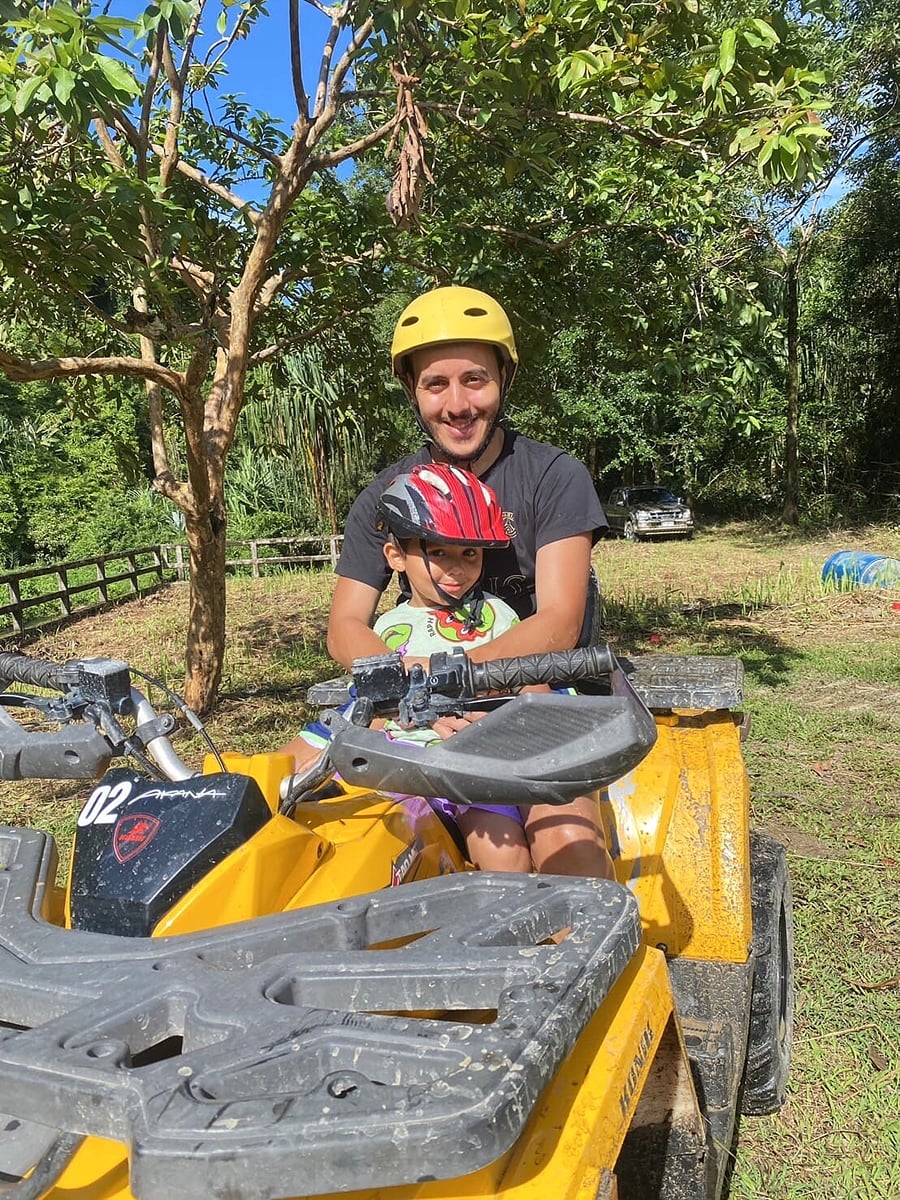 A father and child in helmets on a yellow ATV