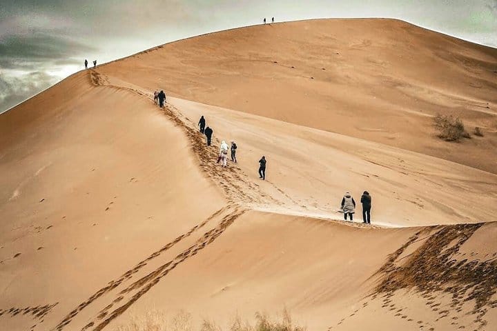 Golden desert dune under blue sky in southeastern Kazakhstan.