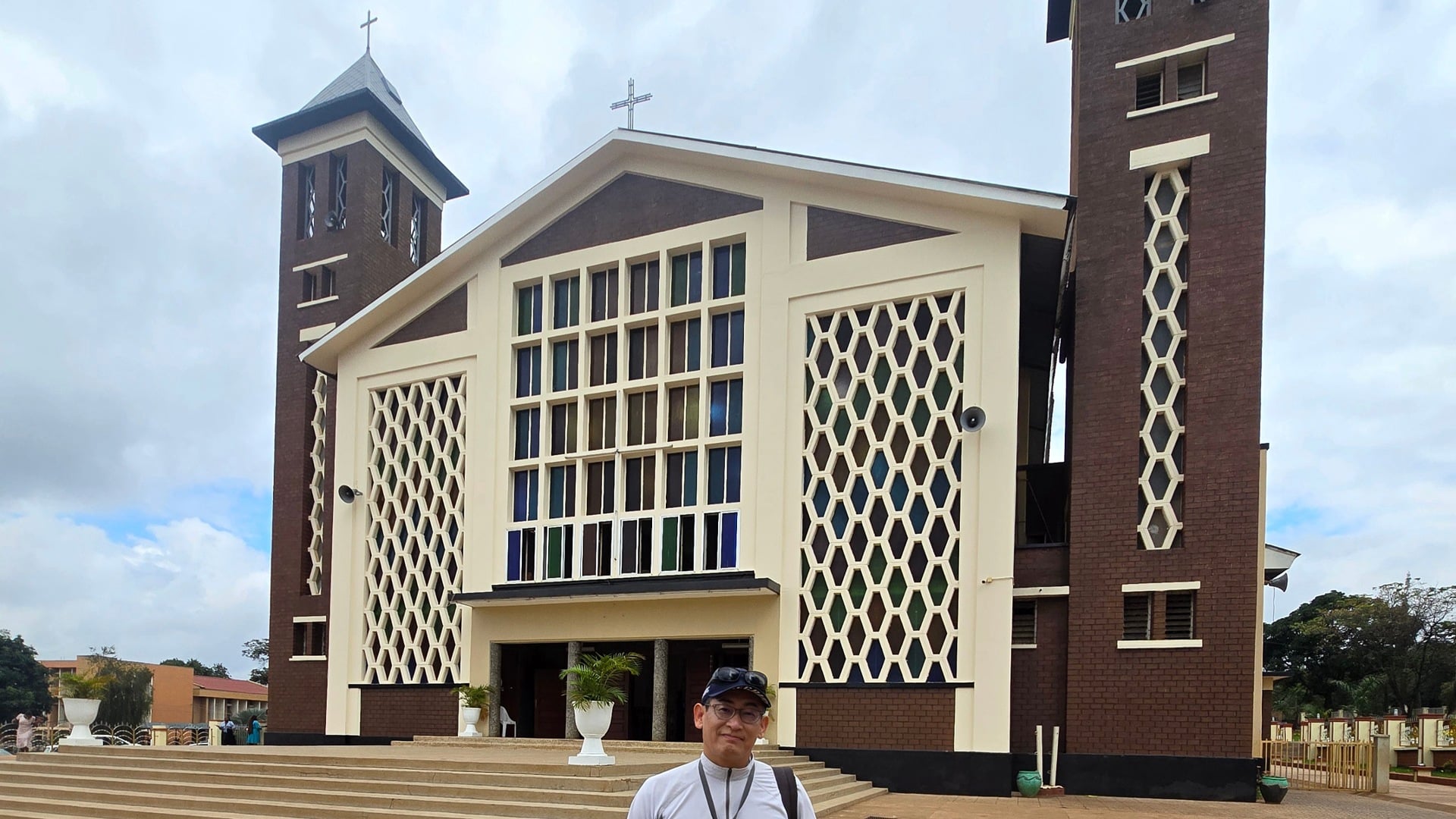 A male traveler standing in front of the Christ the King Cathedral entrance in Moshi.