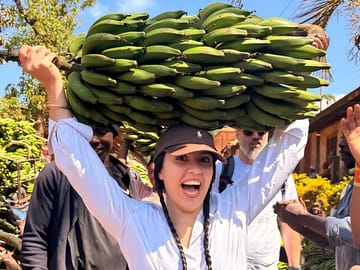 Immersive cultural fun: balancing a bunch of green bananas during a Moshi village tour.