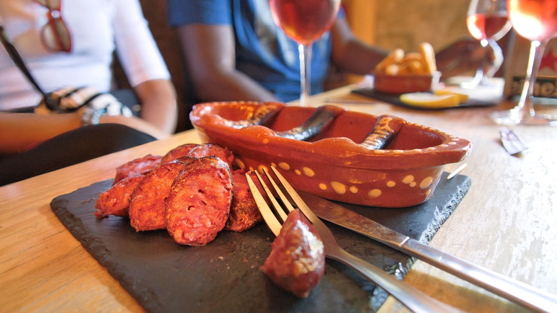 Close-up of grilled Portuguese chorizo freshly sliced after being flambéed in a clay dish