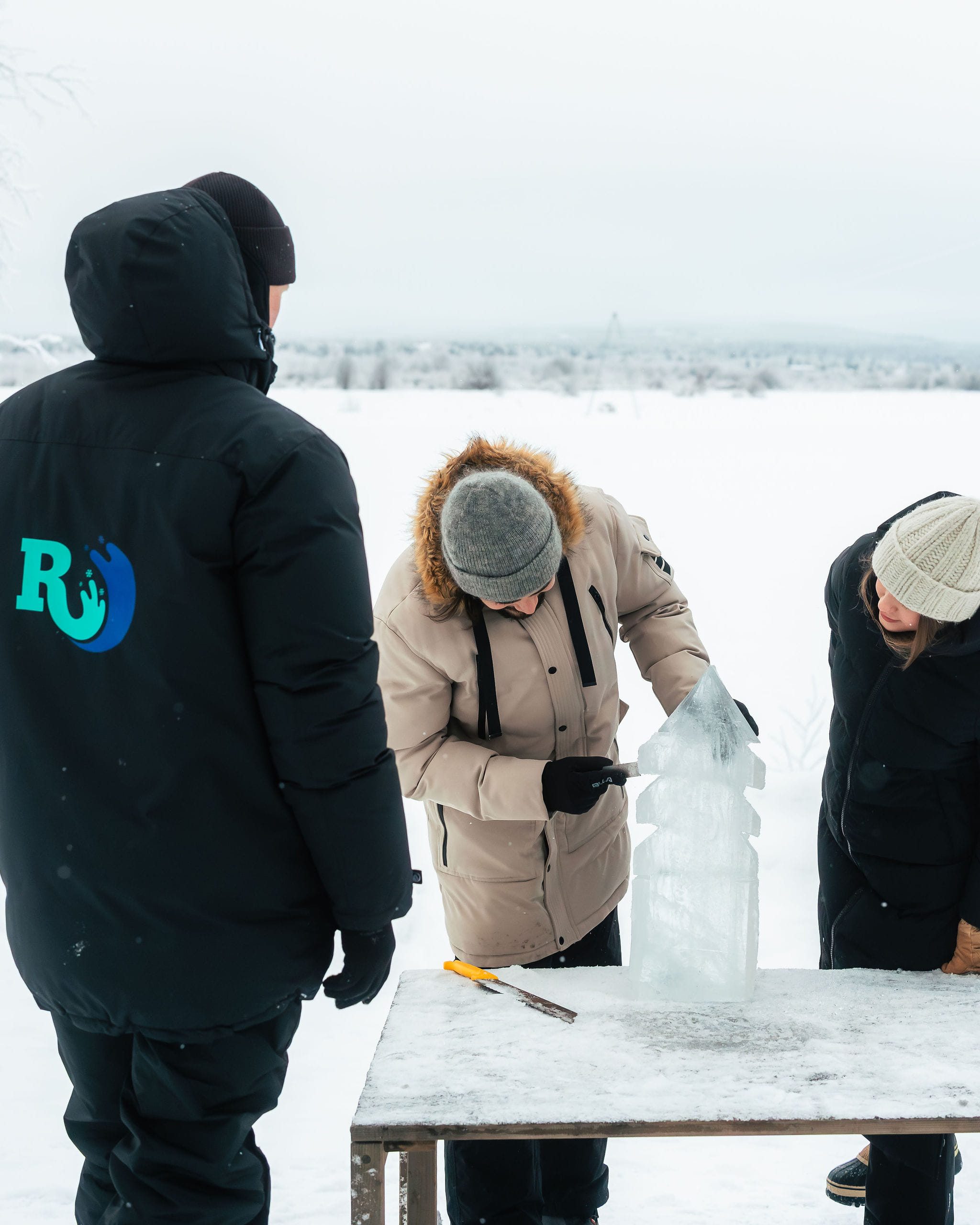 A couple sculpting an ice block with sculpting tools