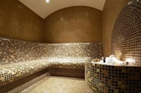 Interior of a modern steam room with warm lighting and tiled seating.