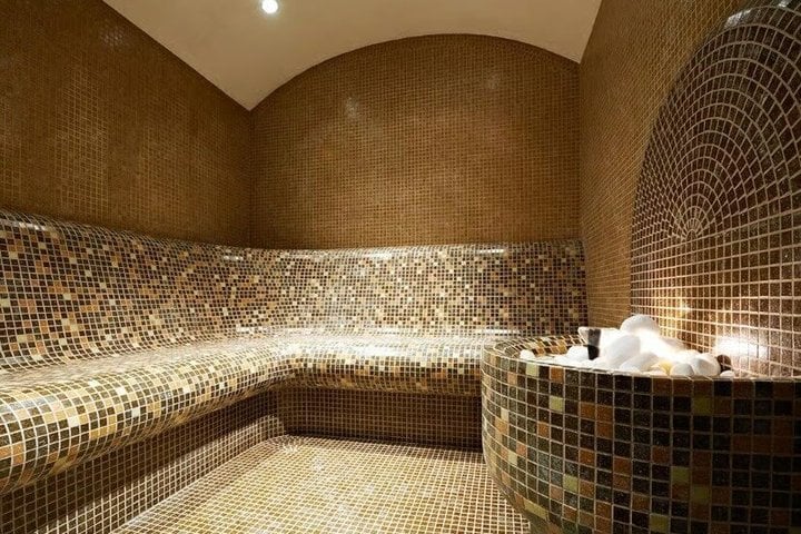Interior of a modern steam room with warm lighting and tiled seating.