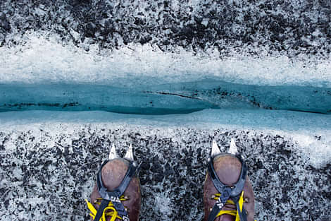 Glacier hiking, hiking shoes with crampons, looking down a crevasse, blue ice