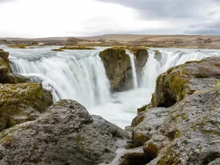 Waterfall surrounded by lush green Icelandic landscape