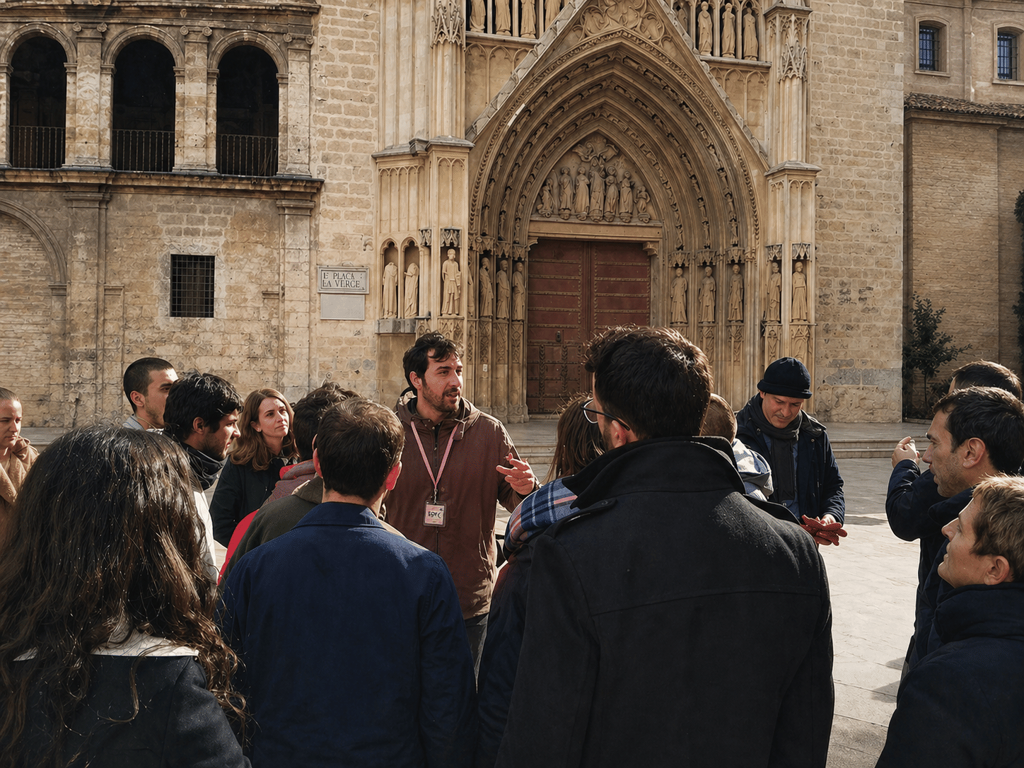 Tour guide explaining Valencia Cathedral to a group of tourists in Plaza de la Virgen, Valencia, Spain