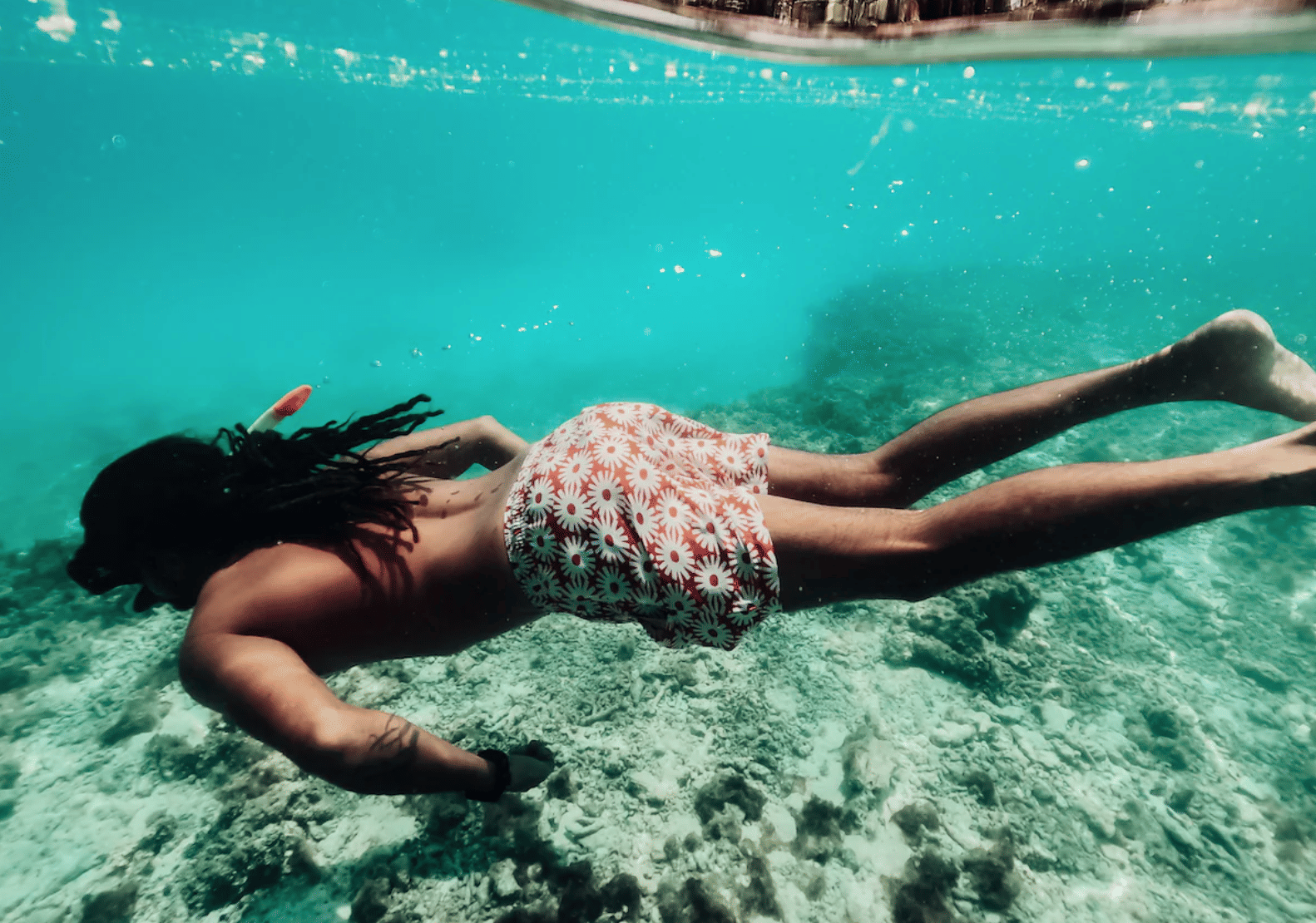 Una persona buceando en las vibrantes y cristalinas aguas de las Maldivas, explorando el mundo submarino.