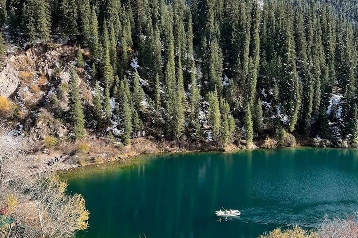 Clear mountain lake with forested slopes and calm reflective water.